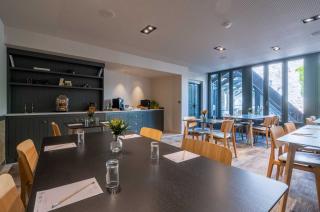 salle avec plusieurs tables et chaises de notre hotel seminaire la rochelle