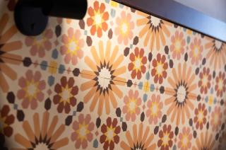 zoom sur la tête de lit aux motifs floraux et géométriques, éclairée par une lumière douce