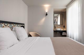 chambre lumineuse avec un grand lit double, décorée dans des tons neutres avec une tête de lit ornée de motifs colorés