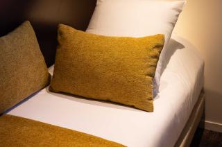 lit simple avec coussin et dessus de lit de couleur jaune